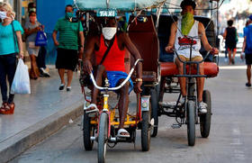 Conductores de bicitaxis con mascarillas en una calle de La Habana