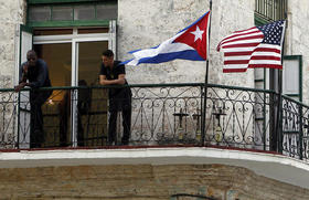 Dos jóvenes cubanos conversan junto a las banderas de Estados Unidos y Cuba, el 17 de marzo de 2016 en La Habana