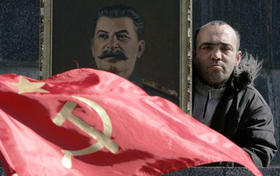 Un ruso con una foto de Stalin y una bandera de la ex Unión Soviética