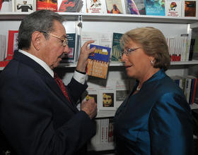 Raúl Castro sostiene el libro 'Nuestros años verde olivo', del chileno Roberto Ampuero, junto a la presidenta Bachelet. (GOBIERNO DE CHILE)
