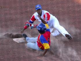 El cubano Héctor Olvera (d) recibe al venezolano Oscar Angulo durante el partido por el grupo B de béisbol
