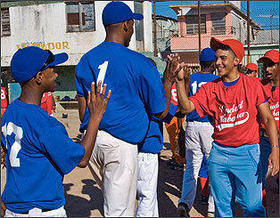 Niños peloteros cubanos, con uniforme rojo, saludan a los jugadores de Estados Unidos, en La Habana