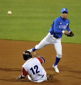 El jugador de Cuba Michel Enríquez (i) se desliza por la base junto a Buk Sung-won (d) de Corea, el jueves 6 de octubre de 2011