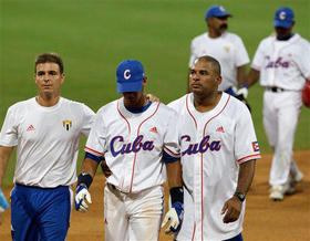 Antonio Castro (izq.) y Orestes Kindelán, acompañan a Yuliesky Gourriel (centro), tras este batear de doble play en el juego final frente a Sudcorea. (AP)