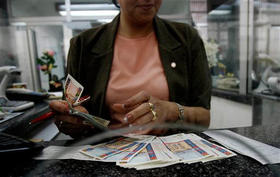 Una mujer cuenta pesos convertibles (CUC) en un banco de La Habana