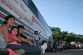 Un grupo de viajeros con intenciones de llegar a Argentina espera en una carretera bloqueada por transportista. (INFOLATAM)