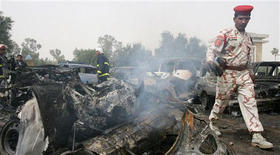La policía y los bomberos iraquíes inspeccionan restos de vehículos, después de una explosión en Bagdad