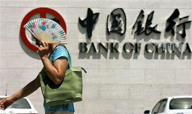 Una mujer se protege del sol a su paso por el Banco de China en Pekín