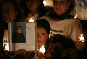 Una mujer muestra una imagen de un secuestrado por las FARC, durante una vigilia para exigir la liberación de los rehenes. (AP)