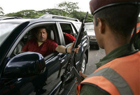 Hugo Chávez, presidente de Venezuela, sostiene el arma de un soldado mientras saluda a las tropas