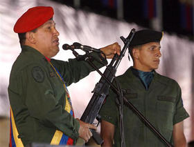 El presidente Hugo Chávez muestra un rifle ruso en la ceremonia por el Día del Ejército. (AP)
