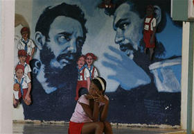 Una joven cubana descansa cerca de un mural dedicado al cumpleaños de Fidel Castro