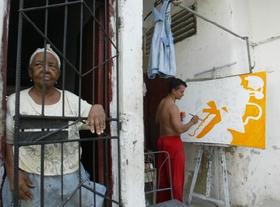 En primer plano, una anciana en un solar de La Habana