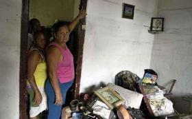 Una mujer muestra la altura que alcanzó el agua en su casa al crecer un río cercano al barrio de Santos Suárez