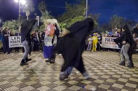 Manifestantes frente al Congreso de Paraguay escenifican una representación en que el país aparece vestido de campesino, al que asedian sombras que lo atacan