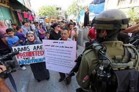 Decenas de palestinos sostienen, frente a unos soldados, carteles en los que se pide que el Estado de Palestina se convierta en el 194 en ser reconocido