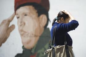 Una mujer pasa junto a una imagen de Hugo Chávez