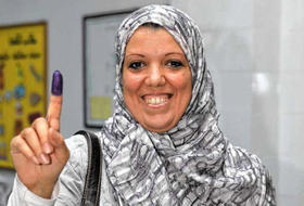 Una mujer libia muestra su dedo entintado luego de votar en las elecciones para elegir un Congreso Nacional, en Trípoli, Libia
