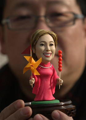 El artista Peng Xiaoping posa con una estatuilla de Hillary Clinton, durante la visita de la secretaria de Estado a Pekín. (AP)