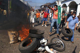 Opositores queman una moto de la policía. (AP)