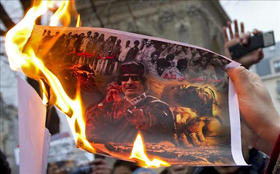 Manifestantes queman una imagen del líder libio Muamar el Gadafi durante una protesta en París, Francia