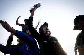 Rebeldes libios celebran mientras se dirigen al frente cerca de la ciudad de Brega, el domingo 27 de marzo de 2011