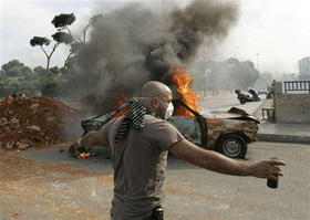Manifestante sostiene una botella de gasolina cerca de un coche en llamas. (AP) Protestas en Beirut