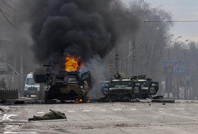 Un vehículo blindado de transporte de personal ruso arde entre vehículos utilitarios ligeros dañados y abandonados después de los combates en Kharkiv, Ucrania, el 27 de febrero de 2022