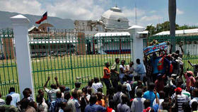 Un día antes de la toma de posesión de Michel Martelly, manifestantes portan un ataúd simbólico con el nombre de René Préval frente al semiderruido Palacio Nacional de Puerto Príncipe