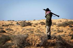 Un rebelde libio permanece armado cerca de un puesto de control en la carretera de Sirte, cerca de Ben Jawad