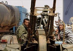 Miembros armados de las fuerzas rebeldes toman este lunes posiciones junto a una batería antiaérea cerca de Ras Lanuf, Libia