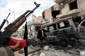 Rebeldes libios junto a un vehículo calcinado en los combates contra las fuerzas leales al líder libio Muamar el Gadafi. EFE