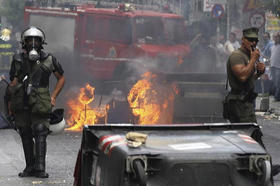 Policías antidisturbios permanecen junto a contenedores incendiados por manifestantes en Atenas
