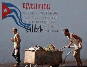 Un hombre empuja una carretilla junto a un cartel alusivo a la revolución en una calle de La Habana, el lumes 5 de abril de 2010.