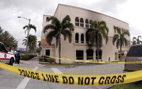 Personal del Departamento de Bomberos investiga en el área exterior de una oficina de viajes a Cuba de Coral Gables, donde fue lanzado un artefacto que causó un incendio en el inmueble