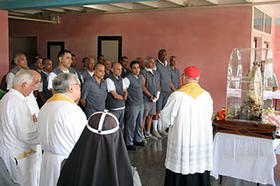 Rolando Sarraf Trujillo, al fondo, delante de un carcelero moreno con espejuelos, asiste a un servicio religioso en prisión. © Gaede