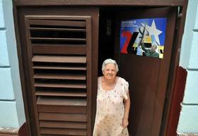 Una anciana se asoma a la puerta de su casa junto a un cartel con la imagen de Fidel Castro