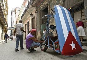 Un cubano repara su bicitaxi en una calle de La Habana