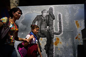 Una mujer y su hija pasan frente a un mural que representa al presidente Donald Trump, en una calle de La Habana, el 16 de junio