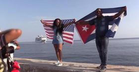 Dos cubanos, con las banderas de Cuba y Estados Unidos, esperan la llegada del Adonia en el Malecón habanero. en esta foto de archivo