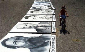 Un niño pasa en bicicleta junto a una serie de carteles para ser usados en una actividad del Gobierno cubano