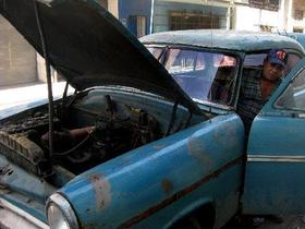 Un cubano trata de arrancar un viejo automóvil estadounidense.