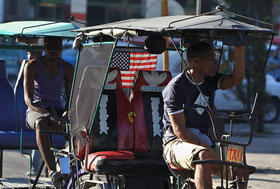 Un bicitaxista con la bandera de EEUU decorando su vehículo espera la llegada de clientes el jueves 18 de diciembre de 2014, en La Habana (Cuba). Un bicitaxista con la bandera de EEUU decorando su vehículo espera la llegada de clientes el jueves 18 de diciembre de 2014, en La Habana (Cuba)