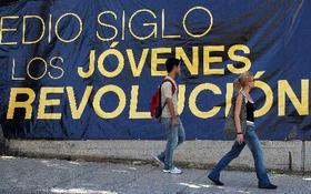 Jóvenes caminan junto a uno de los tantos lemas revolucionarios que se encuentran a diario en las calles de Cuba