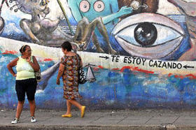 Dos mujeres junto a un mural en una calle de Pinar del Río