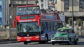 Ómnibus turístico y viejo automóvil estadounidense por las calles de La Habana