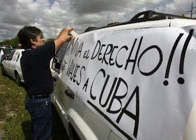 Un hombre pega en su coche un cartel donde reivindica el derecho de viajar a Cuba