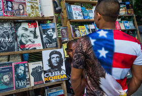 Un hombre con una camiseta con la bandera de Estados Unidos contempla un puesto de venta de libros en La Habana