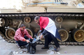 Un par de egipcios limpian cerca de un tanque en el centro de El Cairo, Egipto, el sábado 29 de enero de 2011