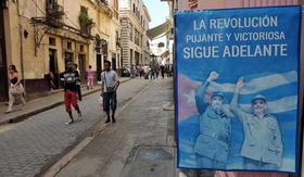Transeúntes caminan por una calle junto a un cartel con las figuras del presidente cubano, Raúl Castro (d), y su hermano, Fidel (2d), en La Habana